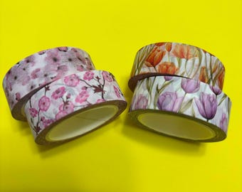 May include: Four rolls of washi tape with floral designs. The rolls are pink, white, and orange with different floral patterns.