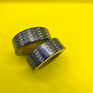 May include: Two rolls of blue and white patterned washi tape. The tape has a striped and star design.