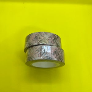 May include: Two rolls of washi tape with a ballet shoe design. The tape is beige with a light pink and gray pattern.
