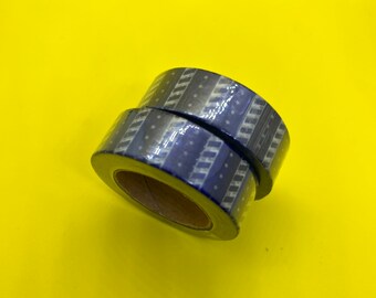 May include: Two rolls of blue and white patterned washi tape. The tape has a geometric design with white stripes and blue polka dots.