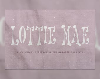 May include: A rectangular graphic display featuring the white text LOTTIE MAE in a stylized font centered on a textured dusty rose background. Below the main title, smaller white text reads A WHIMSICAL TYPEFACE BY THE OCTOBER CREATIVE.