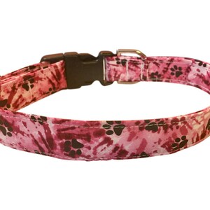May include: Pink dog collar with a paw print pattern and a black plastic buckle.