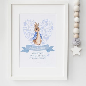 Könnte beinhalten: Ein blauer und weißer illustrierter Druck von Peter Rabbit in einer blauen Jacke, der in einem herzförmigen Blumenmuster steht. Der Druck enthält den Text "Alexander Smith", "Getauft", "19. August 2016" und "St. Mary's Church".