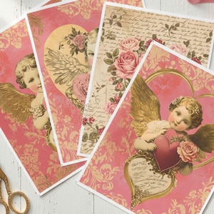 May include: A collection of vintage-style greeting cards with cherub and floral designs. The cards feature a pink and gold color scheme, with cherubs holding hearts and roses. The cards are arranged on a white surface.