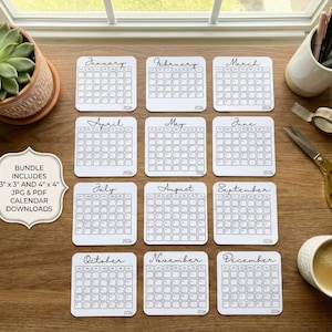 Può includere: Una collezione di calendari bianchi del 2026, ognuno con un mese, disposti su una superficie di legno. Sono presenti anche una pianta grassa in un vaso di terracotta, penne, forbici, nastro adesivo e una tazza di caffè. Il pacchetto include download di calendari JPG e PDF da 7,62 cm x 7,62 cm e 10,16 cm x 10,16 cm.