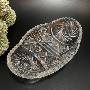 May include: A clear glass oval serving dish with a cut glass design. The dish has a scalloped edge and a raised center.