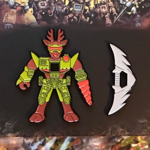 Puede incluir: Un conjunto de dos pines de esmalte que representan un robot verde y rojo con un brazo de taladro y una cuchilla blanca en forma de media luna. Los pines son parte de la colección Beast Pins.