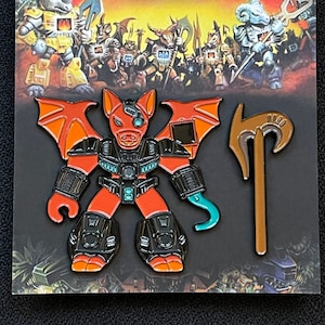 May include: A red and black enamel pin of a cartoon beast with wings and a weapon. The pin is part of a set called "Beast Pins".