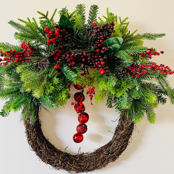 Red berries and bells. A modern  Christmas front door wreath with faux greenery including cedar, pine, Norway spruce and forest pine.