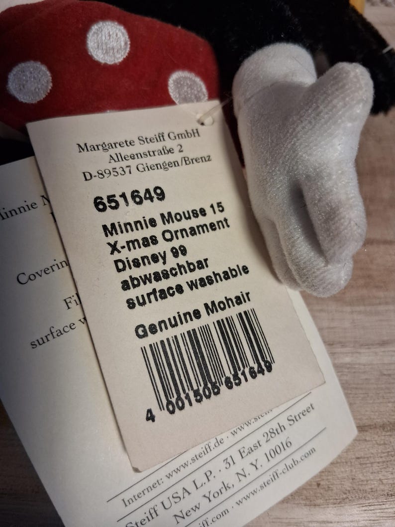 Pu&ograve; includere: Un ornamento natalizio di Minnie Mouse con un fiocco rosso a pois e un guanto bianco. L'etichetta recita "Minnie Mouse 15 X-mas Ornament Disney 99". L'ornamento &egrave; realizzato in mohair genuino.