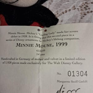 Pu&ograve; includere: Un peluche di Minnie Mouse con un abito nero e rosso. L'etichetta recita "MINNIE MOUSE, 1999" e "14 cm". L'etichetta indica anche che &egrave; stato realizzato a mano in Germania in mohair e velluto in edizione limitata.