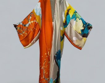 May include: A vibrant, silk kimono with a striking color-block design. One side is bright orange, the other is a cream color with a colorful floral and landscape print. The kimono has wide sleeves and a flowing silhouette, perfect for layering.