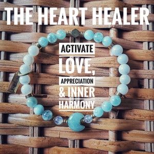 May include: A light blue bracelet with a silver charm that says "The Heart Healer" and the text "Activate Love, Appreciation & Inner Harmony".