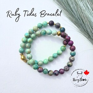 Peut inclure: Un bracelet à double rang de perles vertes et violettes. Le bracelet est fait de pierres naturelles et a un accent doré. Le bracelet s'appelle "Ruby Tides Bracelet".