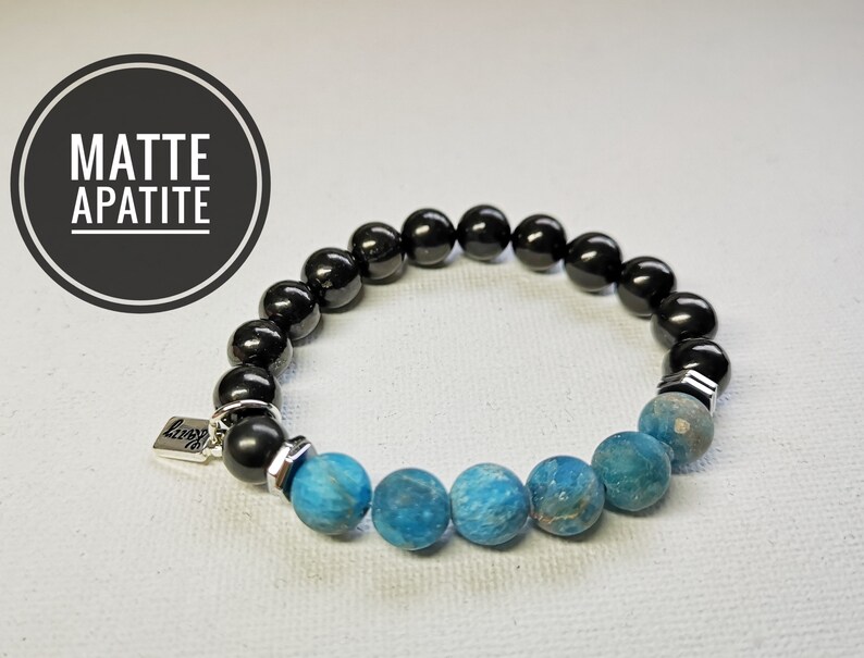 May include: A black and blue beaded bracelet with a silver charm that says "love". The bracelet is made with matte apatite and black onyx beads.