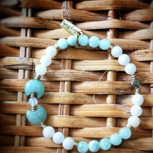 May include: A light blue and white beaded bracelet with a crescent moon charm and a gold tag that says "Happy Soul".