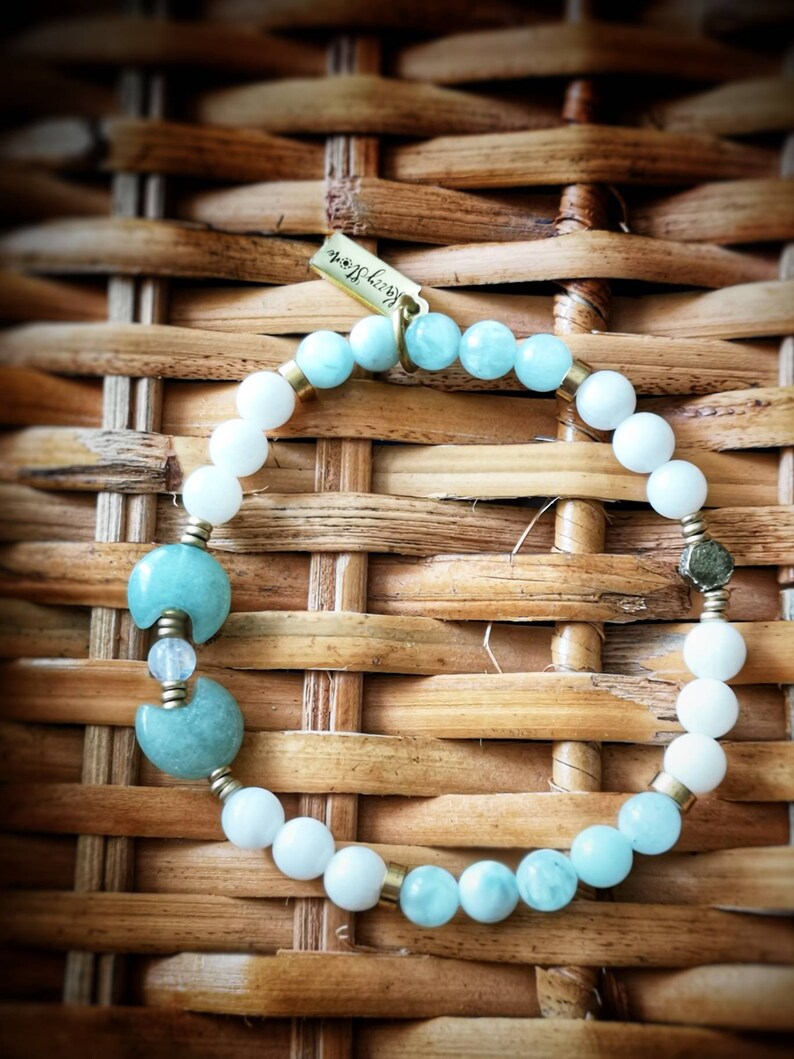 May include: A light blue and white beaded bracelet with a crescent moon charm and a gold tag that says "Happy Soul".