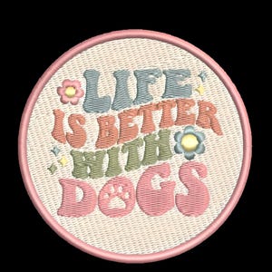 May include: A round, cream-colored patch with pink stitching around the edges. The patch features a colorful, embroidered design with the text "Life is better with dogs" in a retro font. The words are in shades of pink, blue, green, and orange.