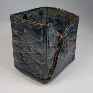 Pu&ograve; includere: Contenitore in ceramica fatto a mano con motivo trapuntato. L'esterno blu scuro ha accenti verdi e arancioni. Un bottone decorativo &egrave; sul lato. Il contenitore di forma quadrata &egrave; adatto per contenere piccoli oggetti.