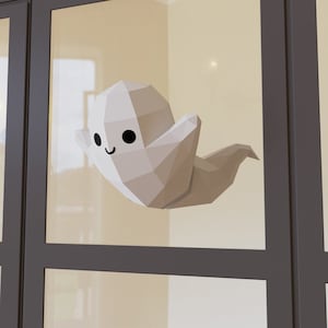 May include: A white origami ghost with a smiling face, on a glass window pane.