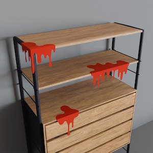 May include: A black metal shelving unit with four wooden shelves and three drawers. The shelves and drawers have red paint dripping down the edges.