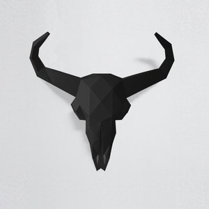 Puede incluir: Decoración de pared de cráneo de toro de origami negro. El cráneo está hecho de papel y tiene un diseño geométrico.