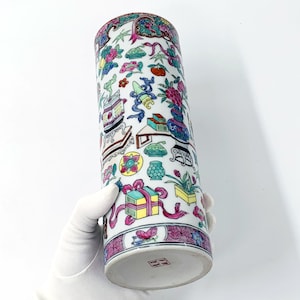 Può includere: Un vaso cilindrico in porcellana bianca con un design floreale e geometrico colorato. Il vaso è decorato con fiori, uccelli e altri motivi in ​​tinte di rosa, blu, verde, giallo e rosso.