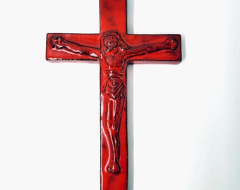 May include: A red crucifix with a detailed depiction of Jesus Christ. The cross is a deep red color with a glossy finish, and the figure of Christ is intricately carved, showcasing the religious theme.