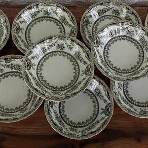 Może przedstawiać: Zestaw dziewięciu vintage ceramicznych misek z zielono-białym wzorem kwiatowym. Miski są wszystkie tego samego rozmiaru i kształtu, a ich brzegi są lekko faliste.