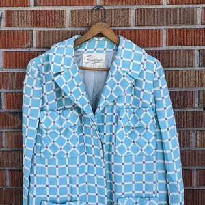 May include: A light blue blazer with a white and light blue checkered pattern. The blazer has a collar, long sleeves, and two pockets on the front. The label on the inside of the blazer reads "Simpson's".