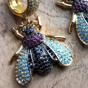 May include: Gold bee earrings with black and turquoise enamel and red and black rhinestones.