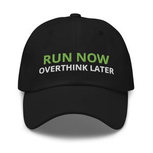 May include: A black baseball cap featuring embroidered text on the front. The words RUN NOW are stitched in lime green, while the words OVERTHINK LATER are stitched in white directly below. The cap has a structured crown and a curved brim.