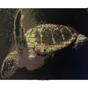May include: A close-up of a green and black pixelated image of a turtle on a black background.