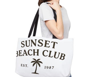 May include: White tote bag with black handles. The bag displays the text "SUNSET BEACH CLUB" in dark brown, with a palm tree graphic and the text "EST. 1987". A stylish beach-themed accessory.