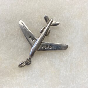 May include: Silver airplane charm with the numbers 925 and 4300 stamped on the wings.