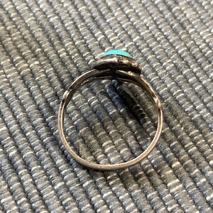 K&ouml;nnte beinhalten: Ein silberner Ring mit einem t&uuml;rkisfarbenen Stein, der in einem dekorativen Design gefasst ist.