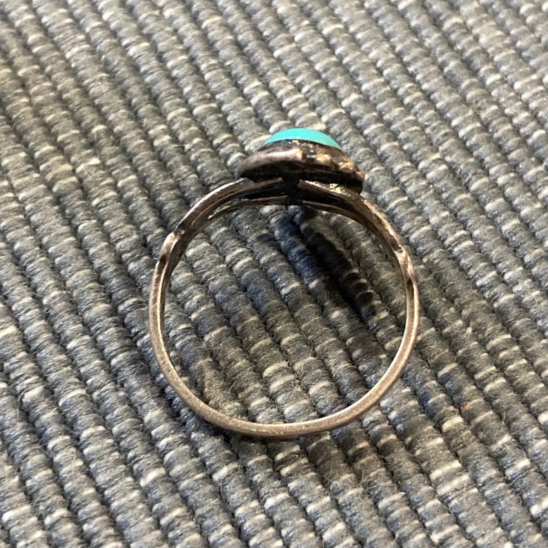 K&ouml;nnte beinhalten: Ein silberner Ring mit einem t&uuml;rkisfarbenen Stein, der in einem dekorativen Design gefasst ist.