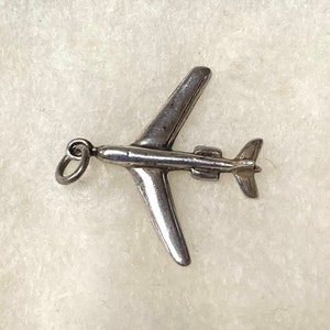 May include: Silver airplane charm with a loop for attaching to a necklace or bracelet.