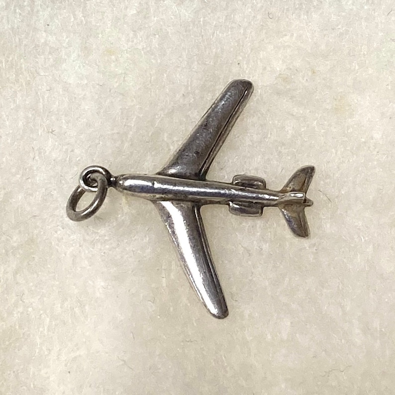 May include: Silver airplane charm with a loop for attaching to a necklace or bracelet.