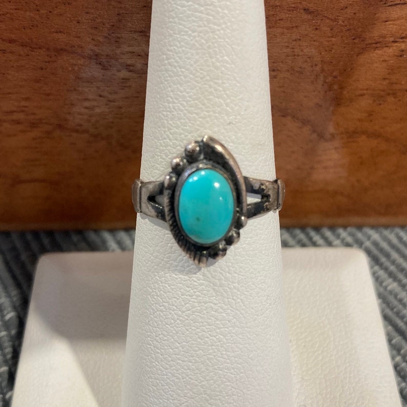 K&ouml;nnte beinhalten: Ein silberner Ring mit einem t&uuml;rkisfarbenen Stein, der in einem dekorativen Design gefasst ist.