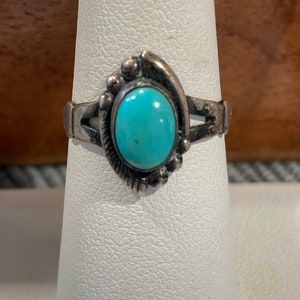 K&ouml;nnte beinhalten: Ein silberner Ring mit einem T&uuml;rkis-Stein, der in einem dekorativen Design gefasst ist.