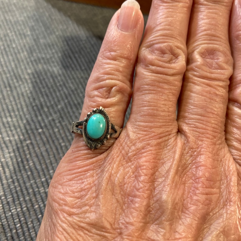 K&ouml;nnte beinhalten: Ein silberner Ring mit einem T&uuml;rkis-Stein, der in einer dekorativen silbernen Fassung sitzt. Der Ring befindet sich an einem Finger.