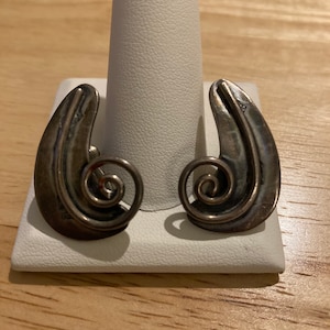 May include: A pair of silver earrings with a curved, abstract design. Each earring features a spiral detail.