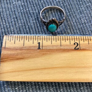 K&ouml;nnte beinhalten: Ein silberner Ring mit einem t&uuml;rkisfarbenen Stein, der in einer silbernen Fassung sitzt. Der Ring hat einen Durchmesser von etwa 2,5 cm.