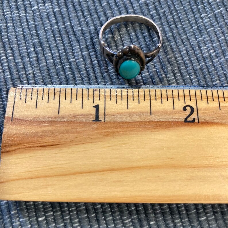 K&ouml;nnte beinhalten: Ein silberner Ring mit einem t&uuml;rkisfarbenen Stein, der in einer silbernen Fassung sitzt. Der Ring hat einen Durchmesser von etwa 2,5 cm.