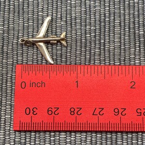 May include: A silver airplane charm measuring approximately 1 inch in length. The charm is detailed with a small propeller and is perfect for adding a touch of travel to jewelry.
