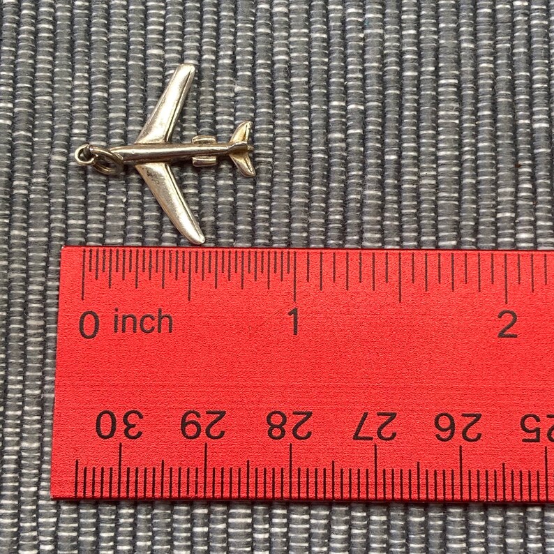 May include: A silver airplane charm measuring approximately 1 inch in length. The charm is detailed with a small propeller and is perfect for adding a touch of travel to jewelry.
