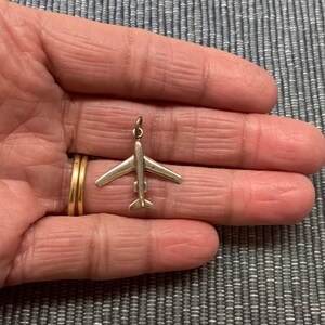 May include: A silver airplane charm pendant. The charm is detailed and has a realistic design.