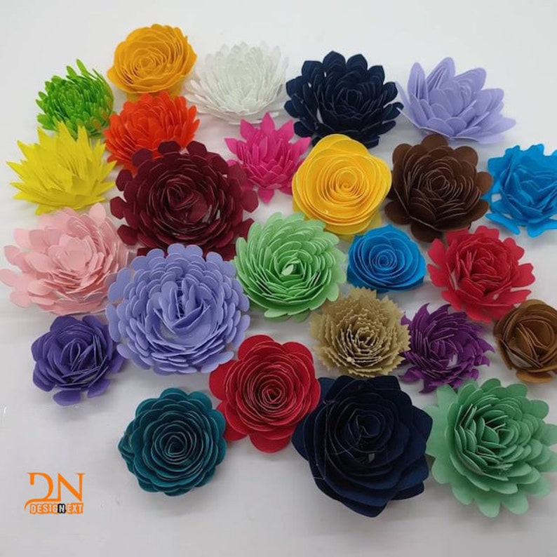 May include: Assortment of paper flowers in various colours, including red, green, blue, purple, yellow, and brown. The flowers are all made of paper and have a layered, three-dimensional appearance.