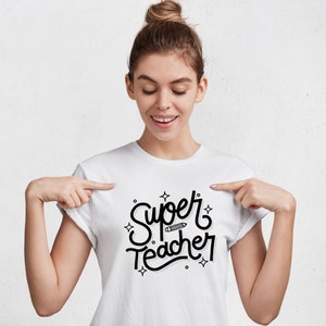 Op de afbeelding: Wit T-shirt met zwarte tekst die "Super Teacher" zegt met een potloodgrafiek.